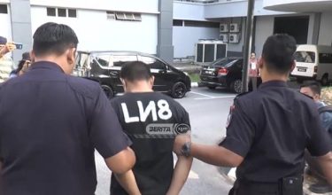 Tertuduh diiringi polis ketika tiba di mahkamah