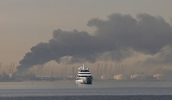 A yacht sails past a plume of smoke rising from the port of Jebel Ali following a reported Iranian strike in Dubai on March 1, 2026. Fresh blasts were heard across the Gulf cities of Dubai, Doha and Manama on Sunday morning after a day of Iran strikes in the region in retaliation for US and Israeli attacks. (Photo by Fadel SENNA / AFP)