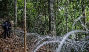 Anggota polis meninjau kawat duri yang memisahkan sempadan antara Malaysia dan Thailand ketika tinjauan khas kawasan laluan sempadan Wang Kelian. Foto BERNAMA
