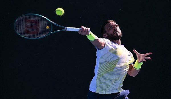 Bosnia's Damir Dzumhur hits a return against Canada's Liam Draxl during their men's singles match on day one of the Australian Open tennis tournament in Melbourne on January 18, 2026. (Photo by WILLIAM WEST / AFP) / -- IMAGE RESTRICTED TO EDITORIAL USE - STRICTLY NO COMMERCIAL USE --