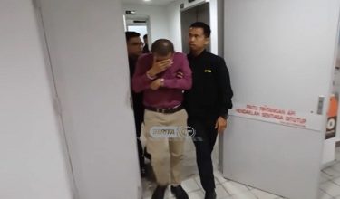 Tertuduh diiringi pegawai SPRM sebaik tiba di mahkamah