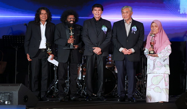 Datuk Seri Dr. Ahmad Zahid Hamidi ketika menyampaikan anugerah ikon seni kepada Gitaris terkenal, Man Kidal (kiri), penyanyi terkenal, Datuk David Arumugam (dua, kiri) dan Pelakon terkenal, Margaret Gan (kanan) pada Konsert Budi Kasih Malaysia / BERNAMA