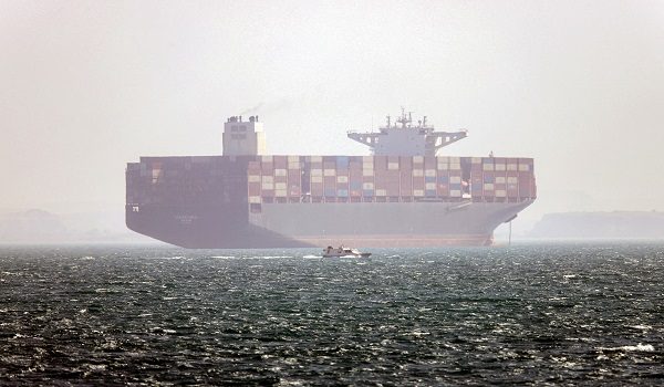 In this picture obtained from Iran's ISNA news agency and taken on May 2, 2026, the Iran-flagged container vessel Hamouna is pictured while anchored as a small motorboat passes by, in the Strait of Hormuz off Bandar Abbas in southern Iran. Iran's Revolutionary Guards on May 4 denied that any commercial ships had crossed the Strait of Hormuz, after the US military earlier said two US-flagged merchant vessels had transited through the vital waterway. (Photo by Amirhossein KHORGOOEI / ISNA / AFP) /