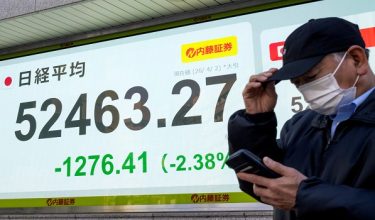 A man stands in front of an electronic quotation board displaying the closing numbers of the Nikkei Stock Average on the Tokyo Stock Exchange on a street in Tokyo on April 2, 2026. (Photo by Kazuhiro NOGI / AFP)