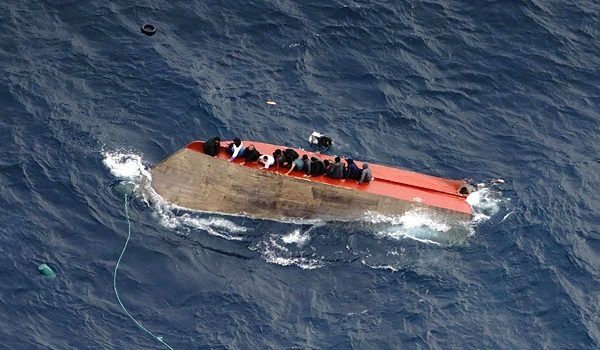 This photo taken on April 4, 2026 and handout on April 5, 2026 by German NGO Sea-Watch, shows migrants seatted on a capsized boat off Libya. Dozens of people are missing after a migrant boat capsized in the central Mediterranean, the NGOs Mediterranea Saving Humans and Sea-Watch said on April 5, 2026 on social media. Two people died and 32 were rescued from the boat, which had left Libya on April 4, 2026 with around 105 people on board, according to Mediterranea Saving Humans. (Photo by Fabian MELBER / SEA-WATCH / AFP) / RESTRICTED TO EDITORIAL USE - MANDATORY CREDIT "AFP PHOTO / FABIAN MELBER / SEA-WATCH" - NO MARKETING NO ADVERTISING CAMPAIGNS - DISTRIBUTED AS A SERVICE TO CLIENTS
