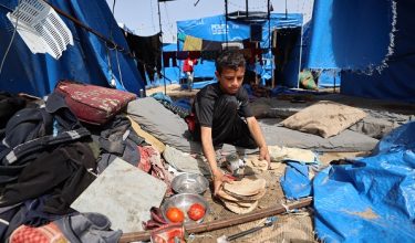 Seorang kanak-kanak Palestin mengutip roti pita di sebuah khemah yang rosak susulan serangan udara Israel yang dilaporkan mengenai khemah pelarian di luar Hospital Syuhada al-Aqsa, Deir el-Balah, tengah Semenanjung Gaza, pada 17 Mei lalu/AFP