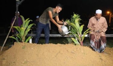 Ahli keluarga menyiram air diatas pusara mangsa nahas jalan raya di Gerik/Foto BERNAMA