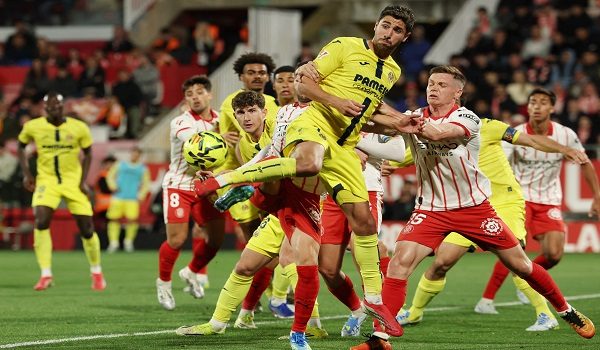 Girona's Ukrainian midfielder #15 Viktor Tsygankov (R) pushes Villarreal's Spanish midfielder #14 Santi Comesana as he kicks the ball during the Spanish league football match between Girona FC and Villarreal CF at Montilivi Stadium in Girona on April 6, 2026. (Photo by Lluis GENE / AFP)