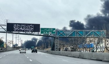 Vehicles move along a highway near plumes of black smoke billowing, in Tehran on March 8, 2026. The United States and Israel launched strikes against Iran on February 28, sparking swift retaliation by the Islamic republic which responded with missile attacks across the region. The war has dragged in global powers, upended the world's energy and transport sectors, and brought chaos to even usually peaceful areas of the volatile region. (Photo by AFP)