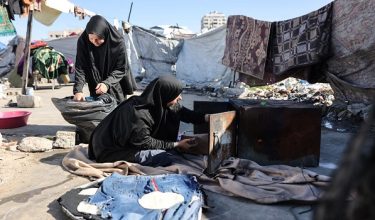 Displaced Palestinian women use a wood stove to begin preparation for Iftar meal, when the day long fast is broken, during the holy fasting month of Ramadan in Gaza City, on the International Women's Day, on March 8, 2026. The majority of Gaza's 2.4 million people have been displaced, often multiple times, by the war that began with Hamas's attack on southern Israel on October 7, 2023. With displaced families living in tented camps, a serious concerns has been raised over their living conditions. (Photo by Omar AL-QATTAA / AFP)