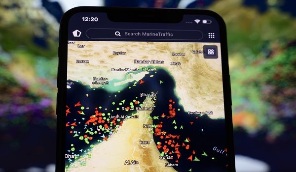 A smartphone screen displaying the MarineTraffic map shows a high concentration of ship beacons in the Strait of Hormuz in Creteil, France, on March 27, 2026. This occurs amid heightened tensions related to incidents involving Iranian drones and oil tankers. (Photo by Samuel Boivin/NurPhoto)NO USE FRANCE