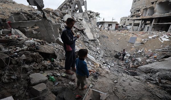 Palestinian children stand near a crater in the Bureij camp in the central Gaza Strip on January 9, 2026 following Israeli attacks. Gaza's civil defence agency said Israeli attacks in the Palestinian territory killed at least 13 people, including five children, despite a ceasefire that has largely halted the fighting. (Photo by Eyad Baba / AFP)
