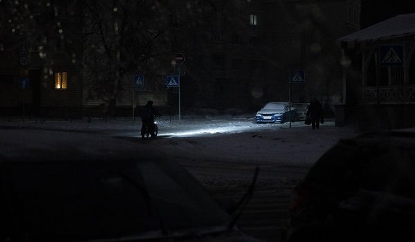 A person rides a bicycle on a non-illuminated street during a power outage in Kyiv on January 9, 2026, following Russian missile and drone attacks on Ukrainian energy infrastructure amid the Russian invasion of Ukraine. Mass heating outages caused by Russian strikes on Kyiv are set to last into the weekend, as the capital's mayor called on residents to temporarily leave the city with sub-zero temperatures expected to fall even lower. (Photo by Andrew Kravchenko / AFP)