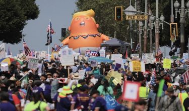A giant inflatable Donald Trump ballon is seen while protestors gather in front of Los Angeles City Hall during the "No Kings" national day of protest in Los Angeles on March 28, 2026. Nationwide protests against US President Donald Trump are expected Saturday as millions of people vent fury over what they see as his authoritarian bent and other forms of cruel, law-trampling governance. It is the third time in less than a year that Americans will take to the streets as part of a grassroots movement called "No Kings," the most vocal and visual conduit for opposition to Trump since he began his second term in January 2025. (Photo by Etienne LAURENT / AFP)