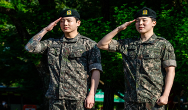 Jungkook (kiri) dan Jimin, anggota kumpulan K-pop sensasi BTS memberikan tabik hormat di sebuah fasiliti sukan luar di Yeoncheon pada 11 Jun 2025, sejurus selepas tamat menjalani 18 bulan khidmat ketenteraan wajib di Korea Selatan / AFP