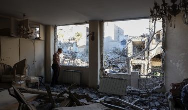 An Iranian resident looks out the window of his damaged home after Israeli-American strikes that according to local media reports destroyed the Rafi-Nia Synagogue and nearby residential buildings in Tehran, on April 7 2026. A synagogue in Tehran was completely destroyed during Israeli-American strikes early April 7, the Mehr news agency and the daily newspaper Shargh reported on the 39th day of the war against Israel and the United States. (Photo by AFP) /