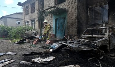A Ukrainian rescuer stands on the porch of a damaged building following an air attack in Kharkiv on June 10, 2026, amid the Russian invasion of Ukraine. (Photo by SERGEY BOBOK / AFP)