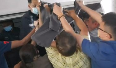 Keluarga tertuuduh menerpa ke arah van polis untuk melindungi wajah tertuduh daripada dirakam media