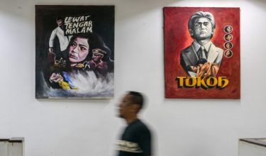 Seorang lelaki berjalan melewati beberapa poster filem seram bertajuk 'Lewat tengah malam' di Pusat Filem Usmar Ismail di Jakarta.