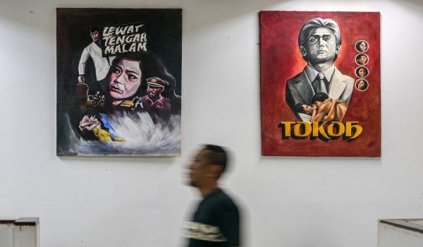 Seorang lelaki berjalan melewati beberapa poster filem seram bertajuk 'Lewat tengah malam' di Pusat Filem Usmar Ismail di Jakarta.
