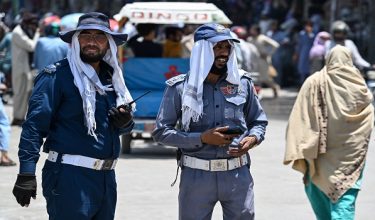 Traffic police personnel cover their heads with cloth as they stand at a road junction amid a heatwave in Rawalpindi on June 9, 2026.  (Photo by Aamir QURESHI / AFP)
