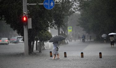 SHENYANG, CHINA - JULY 13: A resident wades through flooded street on July 13, 2026 in Shenyang, Liaoning Province of China. Typhoon Bavi brought heavy rain to the city Shenyang, causing waterlogging on some road sections and affecting local traffic. The Shenyang Flood Control and Drought Relief Headquarters raised the flood control emergency response to Level I at 9:10 a.m. on July 13. (Photo by VCG/VCG )No Use China.