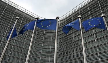 This photograph shows European Union flags in front of the Berlaymont building, the EU Commission headquarters, in Brussels on June 9, 2026. (Photo by Nicolas TUCAT / AFP)