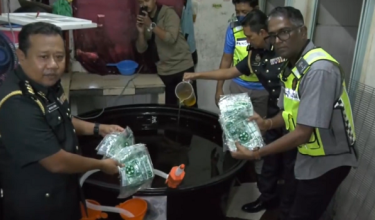 Pengarah KPDN Pulau Pinang, S. Jegan (kanan), menunjukkan minyak masak bersubsidi yang dipindahkan ke dalam tangki industri