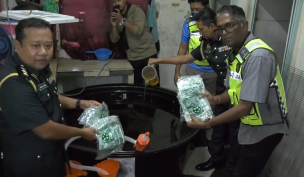 Pengarah KPDN Pulau Pinang, S. Jegan (kanan), menunjukkan minyak masak bersubsidi yang dipindahkan ke dalam tangki industri