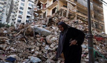A woman walks past a damaged building at the site of an Israeli strike carried out on April 8, at Corniche al-Mazraa in Beirut, Lebanon April 13, 2026. REUTERS/Zohra Bensemra