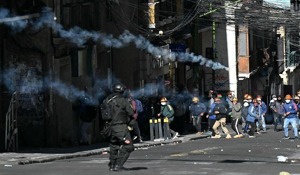 A riot police officer fires tear gas at miners during a march to demand the resignation of Bolivian President Rodrigo Paz, in La Paz, on May 14, 2026. For the past two weeks, workers, farmers, school teachers, Indigenous groups and transport workers have been pressuring the government. Their demands range from wage increases and economic stabilization to opposition to the privatization of public companies. (Photo by AIZAR RALDES / AFP)
