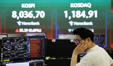 FILE PHOTO: A currency dealer works as an electronic board displays the Korea Composite Stock Price Index (KOSPI) and the Korea Securities Dealers Automated Quotations (KOSDAQ), at the dealing room of a bank in Seoul, South Korea, May 15, 2026.   REUTERS/Kim Hong-Ji/File Photo