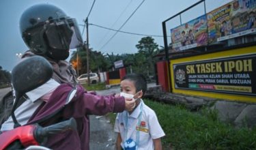 Pekerja kilang Nor Azimah Ali Zaini, 30, memakaikan pelitup muka kepada anaknya, dalam tinjauan FotoBernama susulan keadaan jerebu di Sekolah Kebangsaan Tasek  pada bulan lalu/Foto BERNAMA