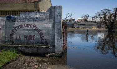 A girl walks across at flooded area at a public primary school used as a shelter for people affected by the passage of tropical cyclone Gezani during the night of February 10 to 11, in Toamasina on February 15, 2026. (Photo by RIJASOLO / AFP)