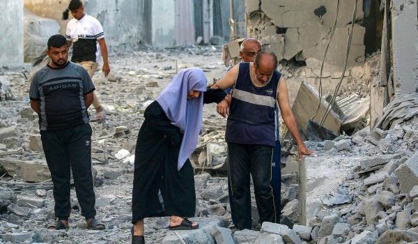 Seorang lelaki membantu wanita melalui runtuhan bangunan yang musnah akibat serangan Israel di kem pelarian Maghazi, Gaza/Foto AFP