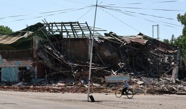 Seorang wanita menunggang basikal berdekatan bangunan yang rosak akibat serangan Rusia di Orikhiv, wilayah Zaporizhzhia, Ukraine/ Foto AFP