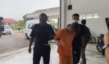Suspek diiringi polis ketika tiba di mahkamah