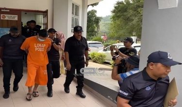 Suspek diiringi polis ketika meninggalkan mahkamah