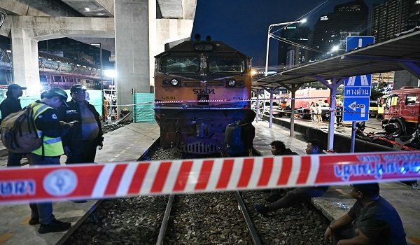 Officials stand next to the front of a train that collided with a bus underneath Makkasan Airport Rail station in Bangkok on May 16, 2026. A collision between a freight train and a bus killed at least eight people and injured more than 30 in the Thai capital Bangkok, emergency services said. (Photo by Lillian SUWANRUMPHA / AFP)