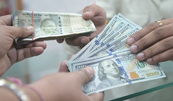 People holding US dollar and Indian rupee currency notes pose for a photograph at a foreign exchange office in Amritsar on May 16, 2026. (Photo by Narinder NANU / AFP)
