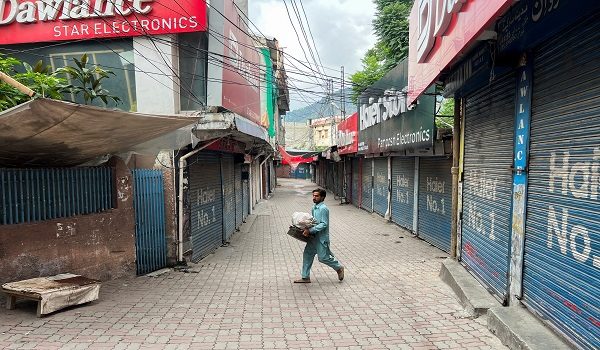 A man walks with his belongings along a closed market, during a shutter-down strike called by the recently banned Joint Awami Action Committee (JAAC), an alliance of civil society groups, in Muzaffarabad, Pakistani Kashmir, June 19, 2026. Picture taken with a mobile phone. REUTERS/Naseer ud Din