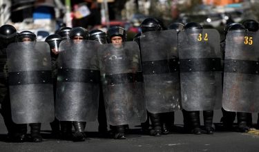 Anggota polis rusuhan berlindung di sebalik perisai ketika demonstrasi membantah kerajaan Presiden Bolivia Rodrigo Paz di sini. / Foto AFP