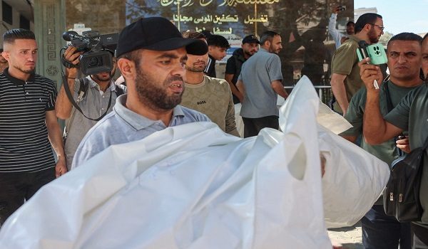 Seorang lelaki membawa jenazah ahli keluarganya yang terkorban dalam serangan udara Israel di sebuah pangsapuri di kawasan al-Sabra di sini. / Foto AFP