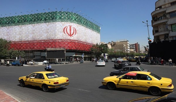 Kenderaan melalui Dataran Enghelab di Tehran, dengan bendera kebangsaan Iran terpampang pada sebuah bangunan. / Foto AFP