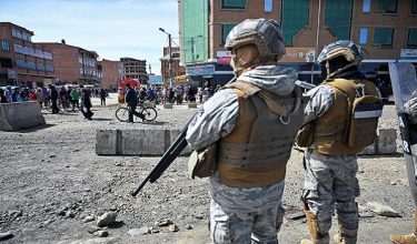 People walk near military personnel standing on guard as they are deployed, after Bolivian President Rodrigo Paz declared a nationwide state of emergency following weeks of violence and blockades, in El Alto, Bolivia, June 20, 2026. REUTERS/Claudia Morales