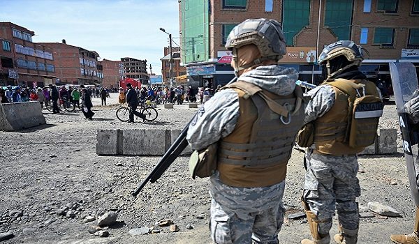 People walk near military personnel standing on guard as they are deployed, after Bolivian President Rodrigo Paz declared a nationwide state of emergency following weeks of violence and blockades, in El Alto, Bolivia, June 20, 2026. REUTERS/Claudia Morales