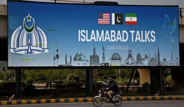 Penunggang motosikal melalui papan iklan rundingan damai AS-Iran di Islamabad/Foto REUTERS
