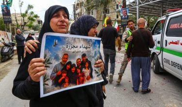 Seorang penduduk memegang plakad ketika upacara pengebumian mangsa yang terbunuh dalam serangan Israel di Deir Qanoun al-Nahr, selatan Lubnan/Foto REUTERS