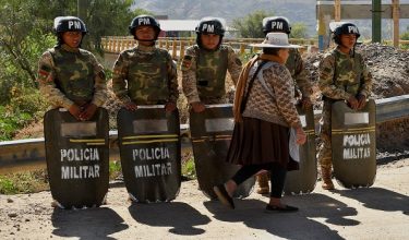 Military personnel stand in formation as they are deployed, while a woman walks past in front of them, after Bolivian President Rodrigo Paz declared a nationwide state of emergency following weeks of violence and blockades,  in Cochabamba, Bolivia, June 20, 2026. REUTERS/Patricia Pinto       TPX IMAGES OF THE DAY