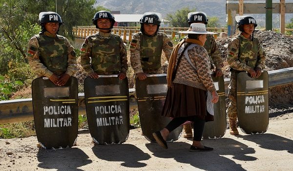 Military personnel stand in formation as they are deployed, while a woman walks past in front of them, after Bolivian President Rodrigo Paz declared a nationwide state of emergency following weeks of violence and blockades,  in Cochabamba, Bolivia, June 20, 2026. REUTERS/Patricia Pinto       TPX IMAGES OF THE DAY